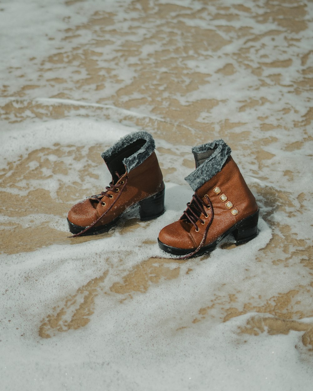 a pair of brown boots sitting on top of snow covered ground