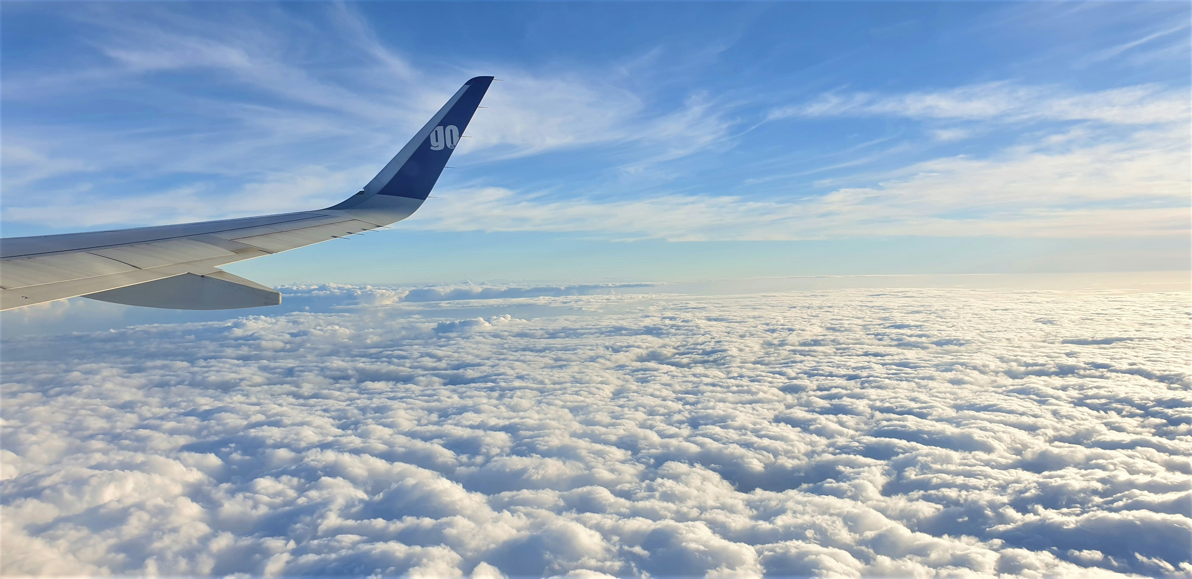 a view of the wing of an airplane above the clouds