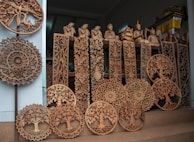 Intricate Thai silk scarves folded neatly beside teakwood carved figurines.