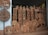Intricately designed wooden carvings featuring circular patterns, trees, and floral motifs. Several Buddhist statues in various poses are arranged among the woodwork, creating a display of artistry and craftsmanship.