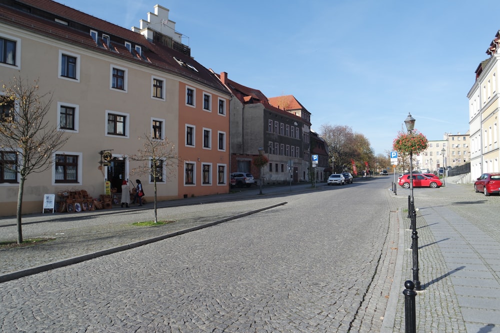 a cobblestone street lined with buildings and parked cars