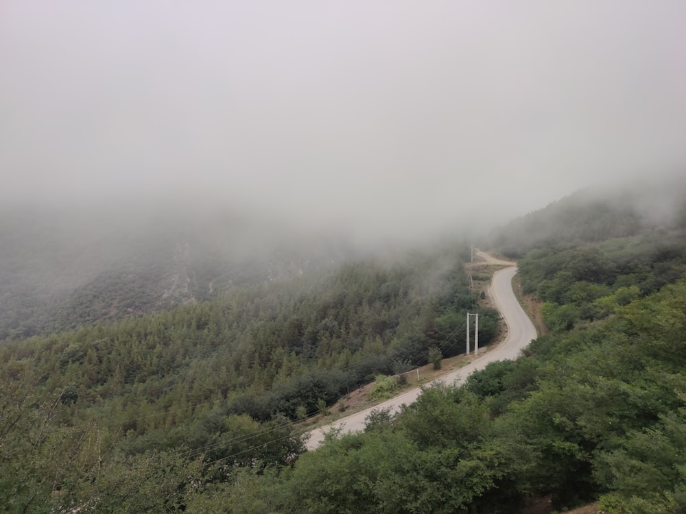 a foggy mountain with a winding road in the foreground