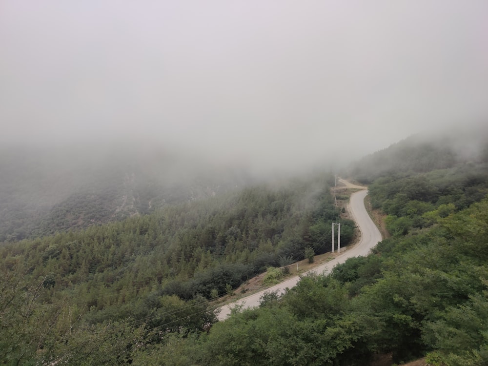 前景に曲がりくねった道がある霧の山