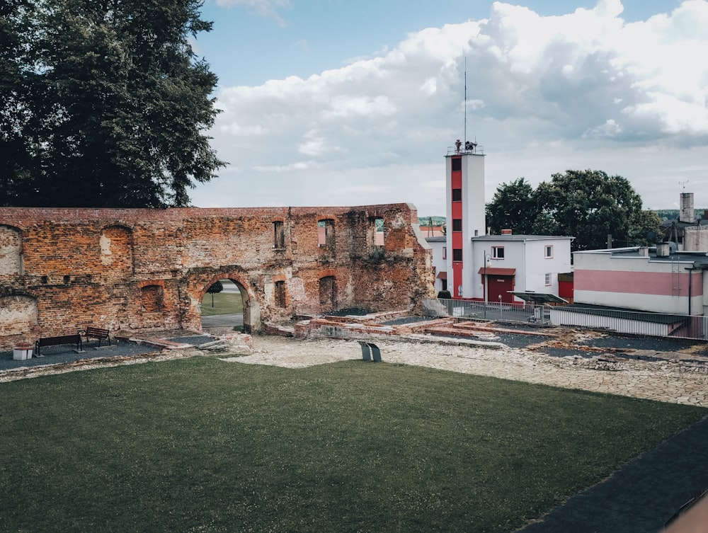 Un antiguo edificio de ladrillo con una torre del reloj en el fondo