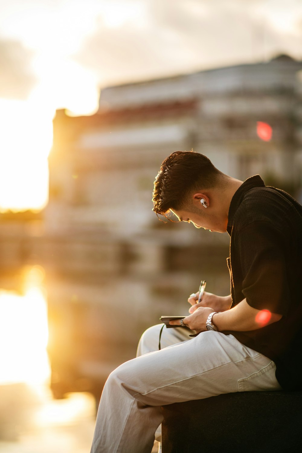 a man sitting on a bench writing on a piece of paper