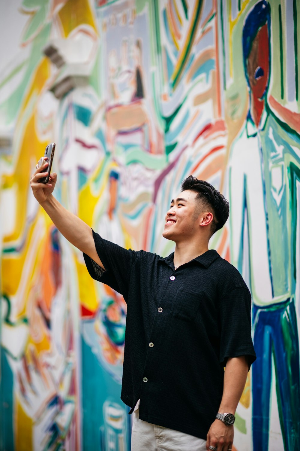 a man taking a picture of a colorful mural