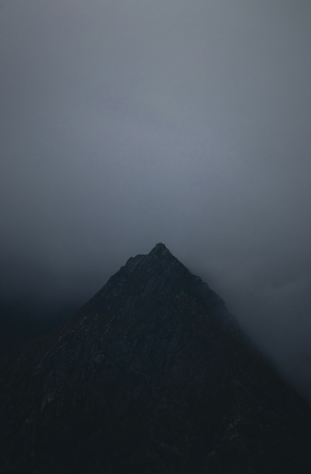a very tall mountain in the middle of a cloudy sky