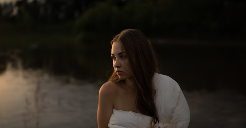 a woman in a white dress standing next to a body of water