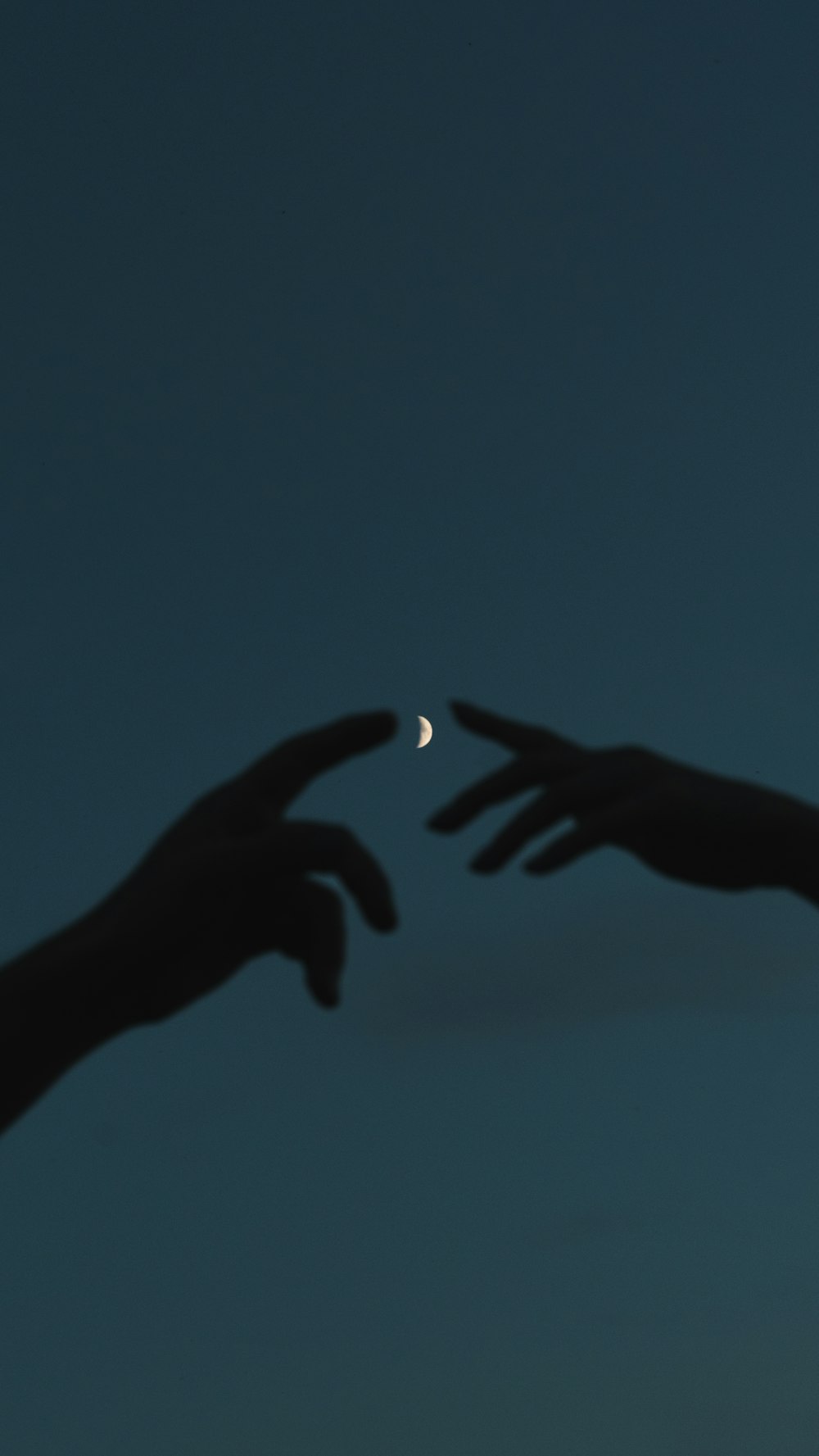 two hands reaching for the moon in the sky