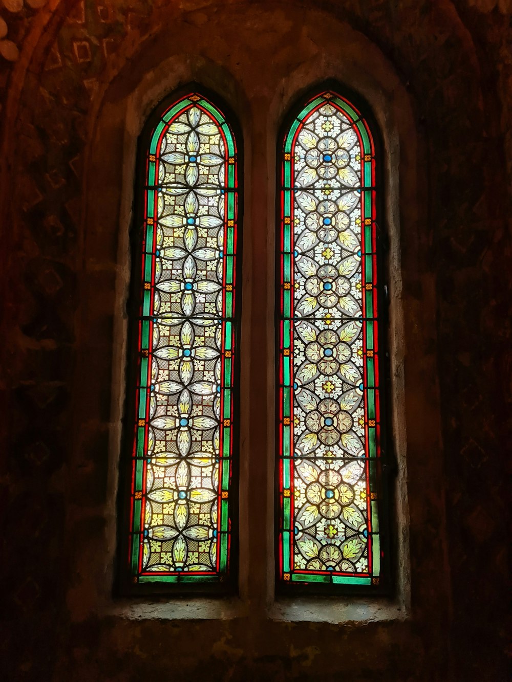 two stained glass windows in a stone building