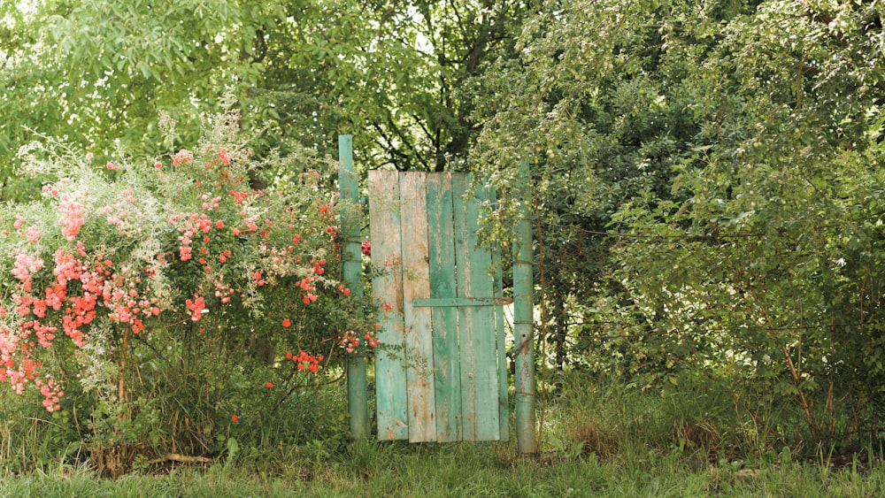 a wooden gate surrounded by trees and flowers