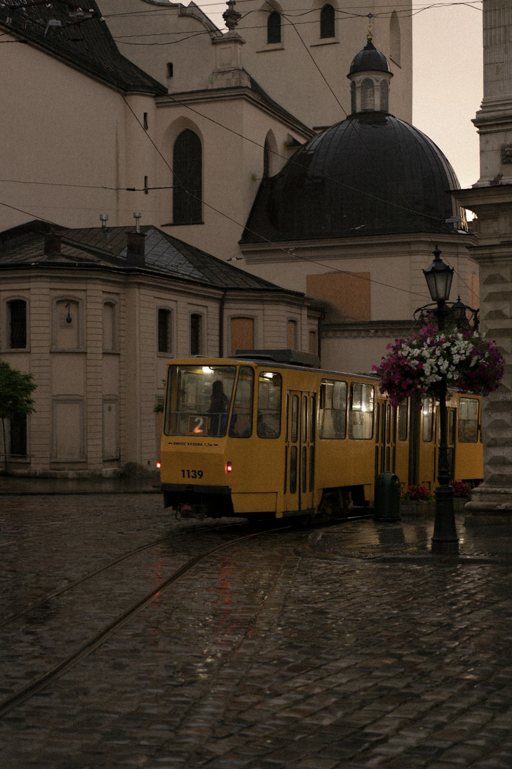 a yellow trolley is on a cobblestone street