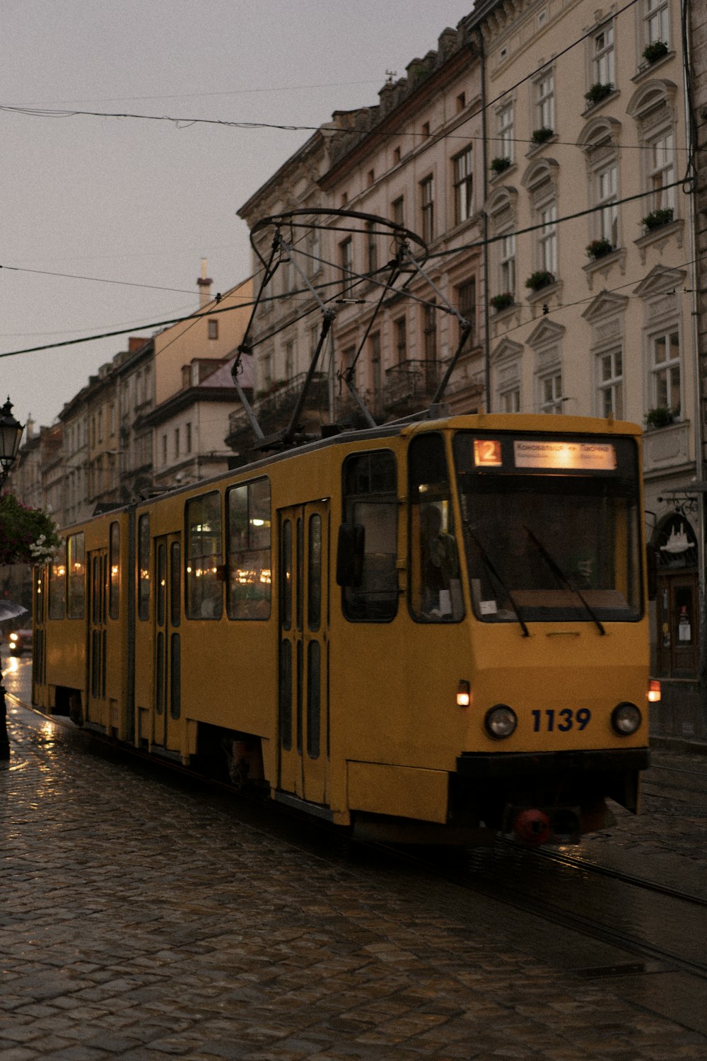 a yellow trolley is on a cobblestone street