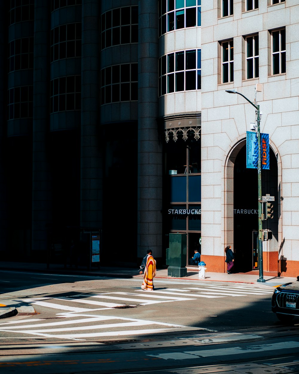 a person crossing a street in front of a tall building