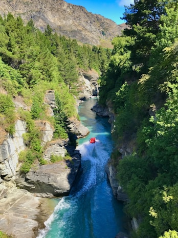 Close-up of a boat cutting through crystal-clear water with rocky cliffs in the background.