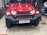 A red SUV with a rugged front bumper and circular LED headlights is parked indoors. The vehicle has a visible license plate and off-road tires, suggesting it is designed for rough terrains. The surrounding area appears to be a garage or workshop with various automotive parts and tools in the background.