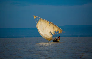 a sailboat with two people on it in the water