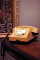 a yellow telephone sitting on top of a wooden table