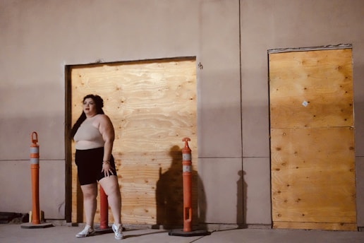 A technician boarding up windows on a vacant house with tools and safety gear.