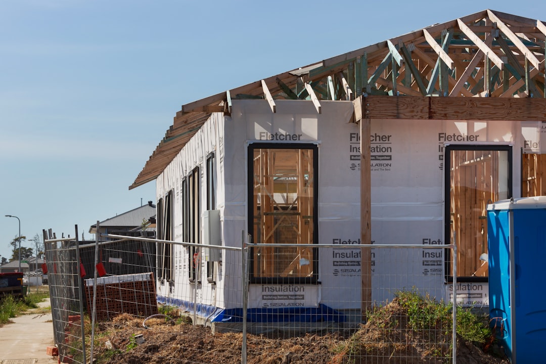 a house under construction with a fence around it, New home construction building site.