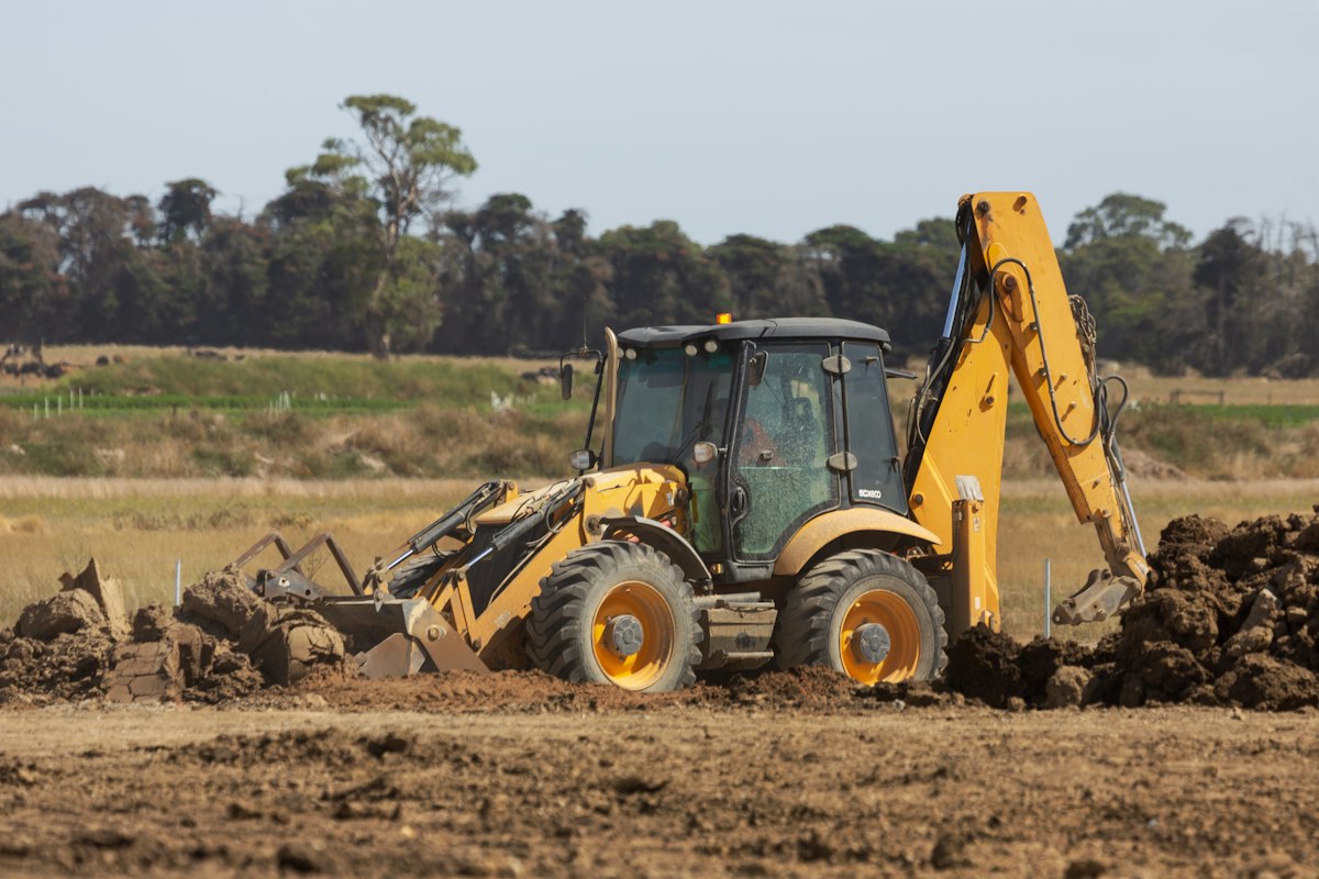 Backhoe loader on exposed soil at an earthwork site.
