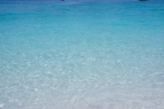 Crystal-clear turquoise waters gently lapping against a white sandy beach at sunrise.