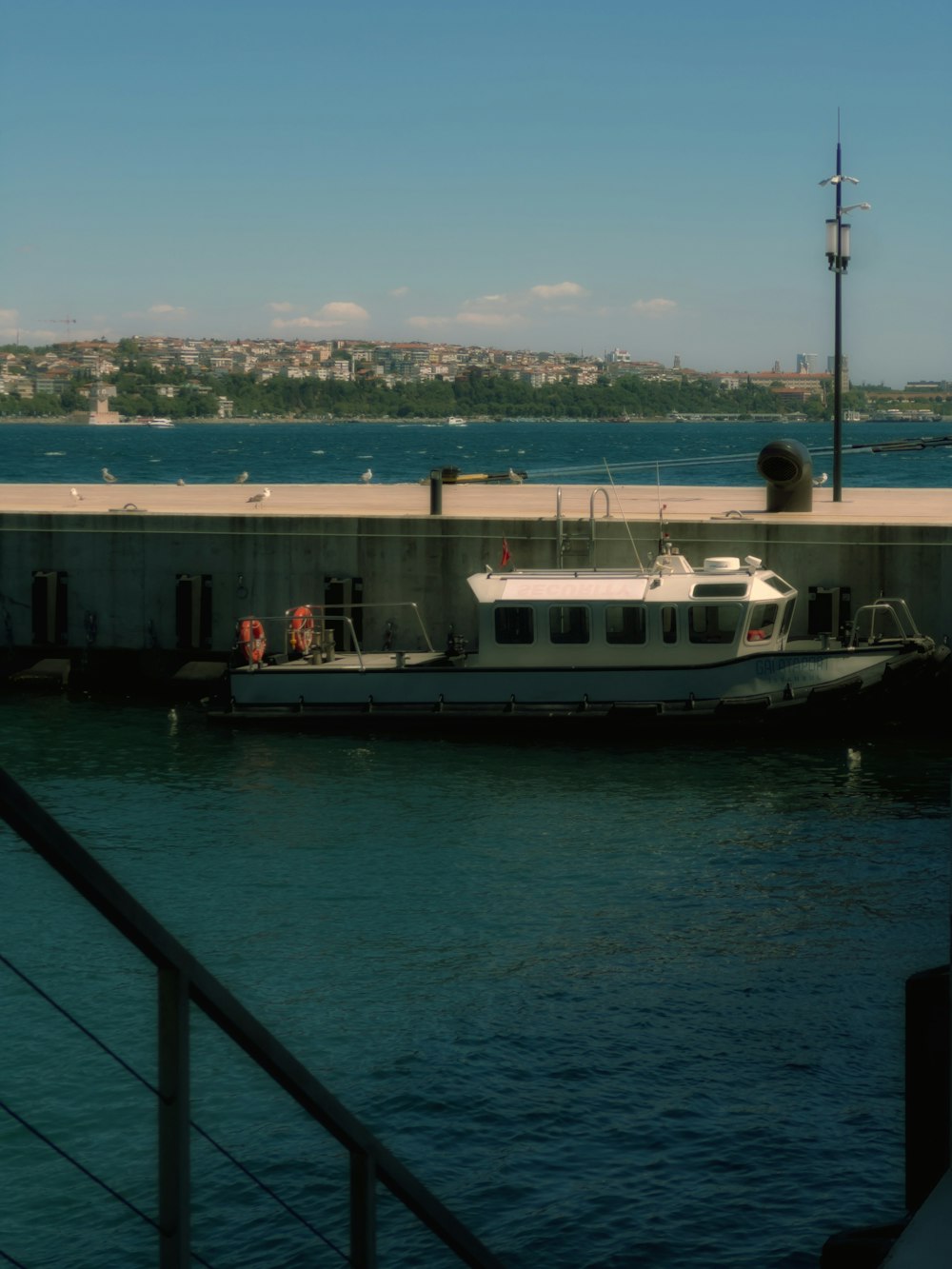 a white boat is docked at a pier