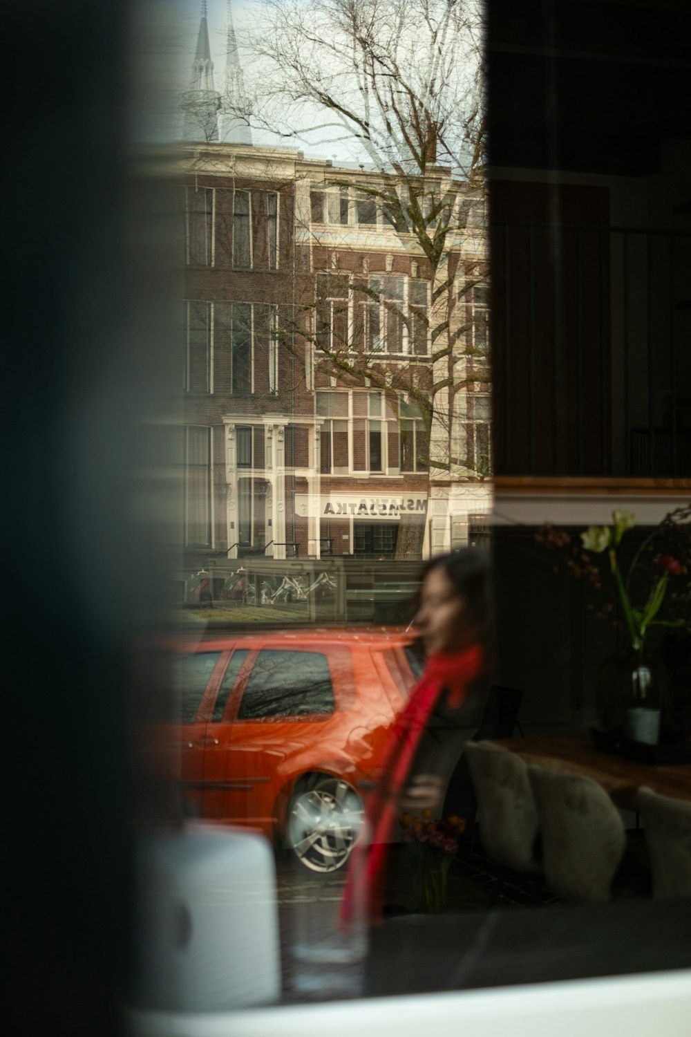 a red car is seen through a window