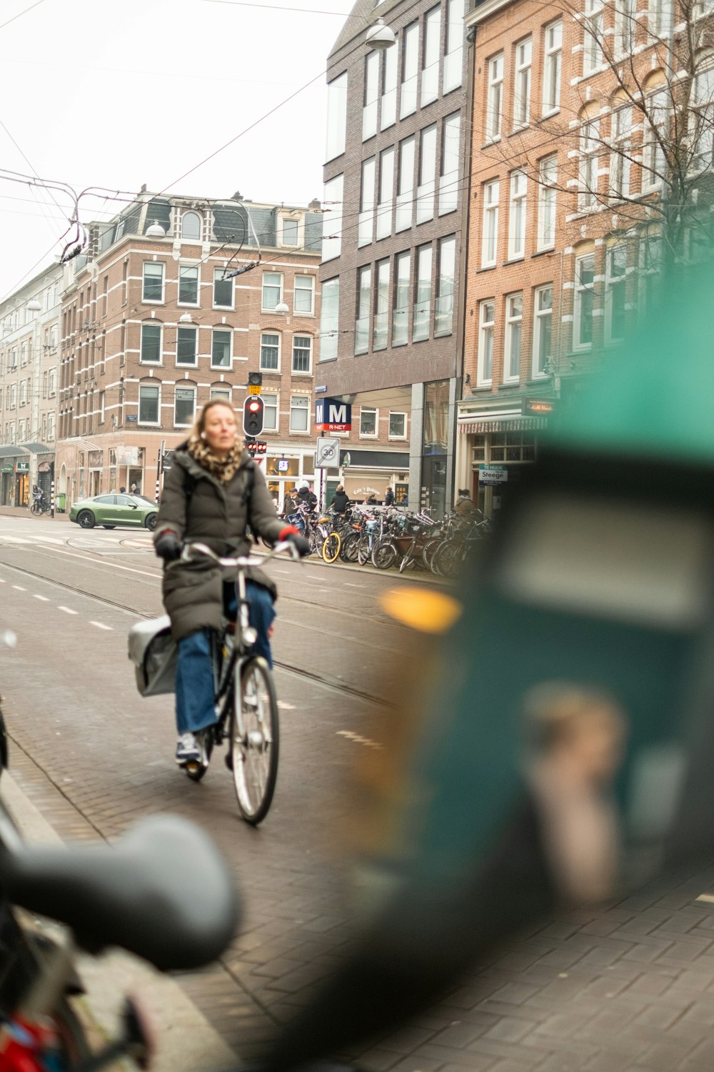 a woman riding a bike down a street next to tall buildings