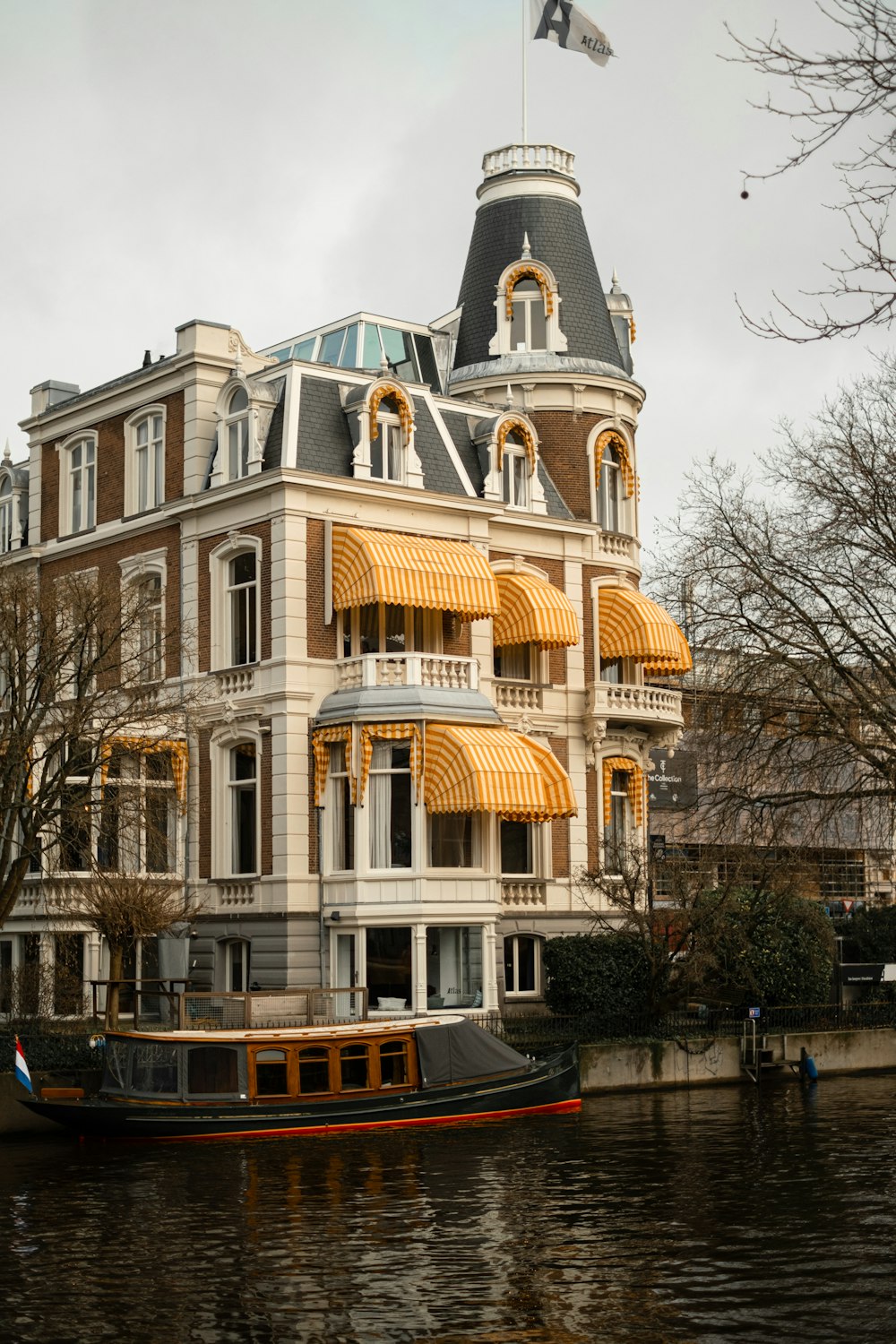 a boat floating down a river next to a tall building