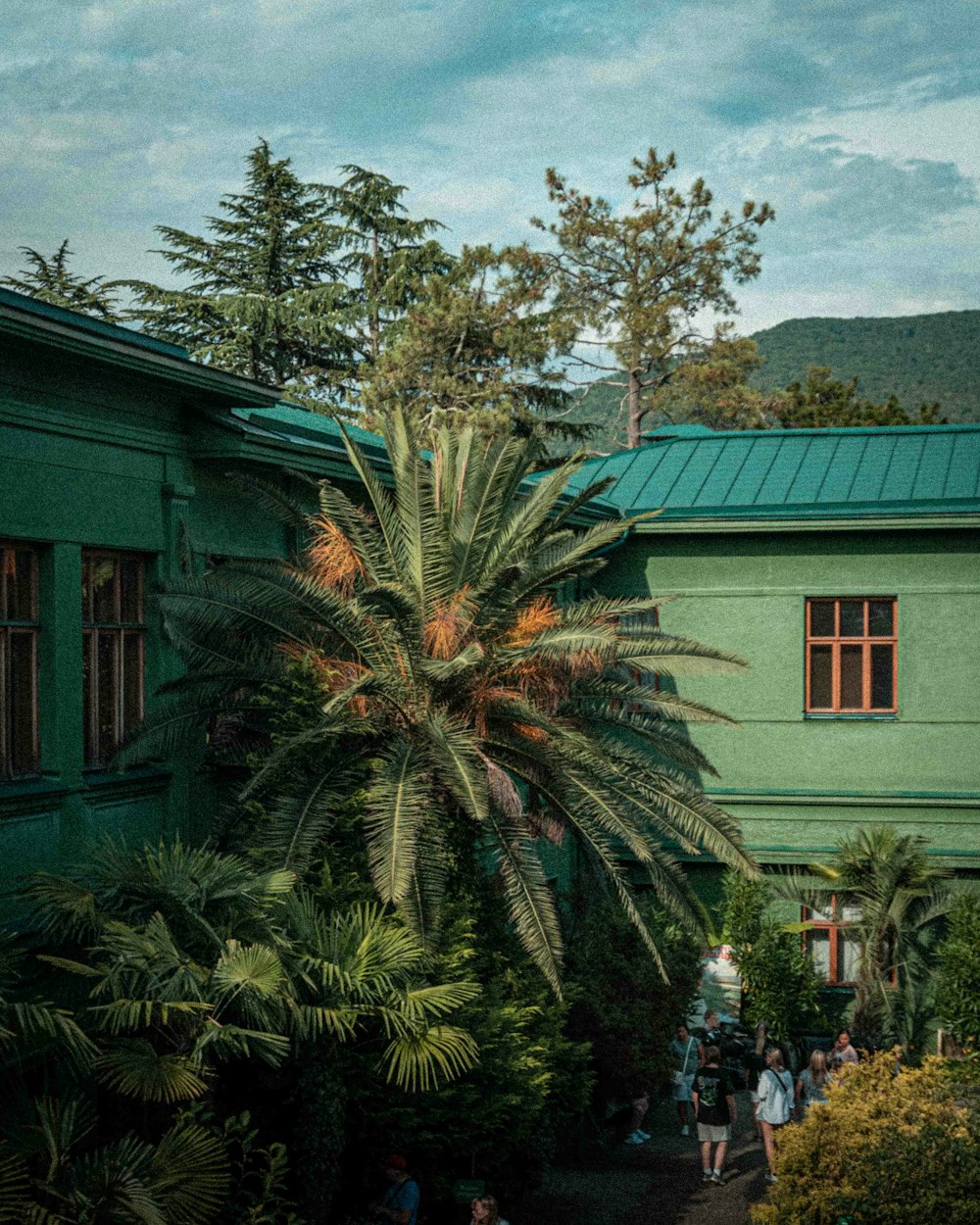 a group of people standing outside of a green building