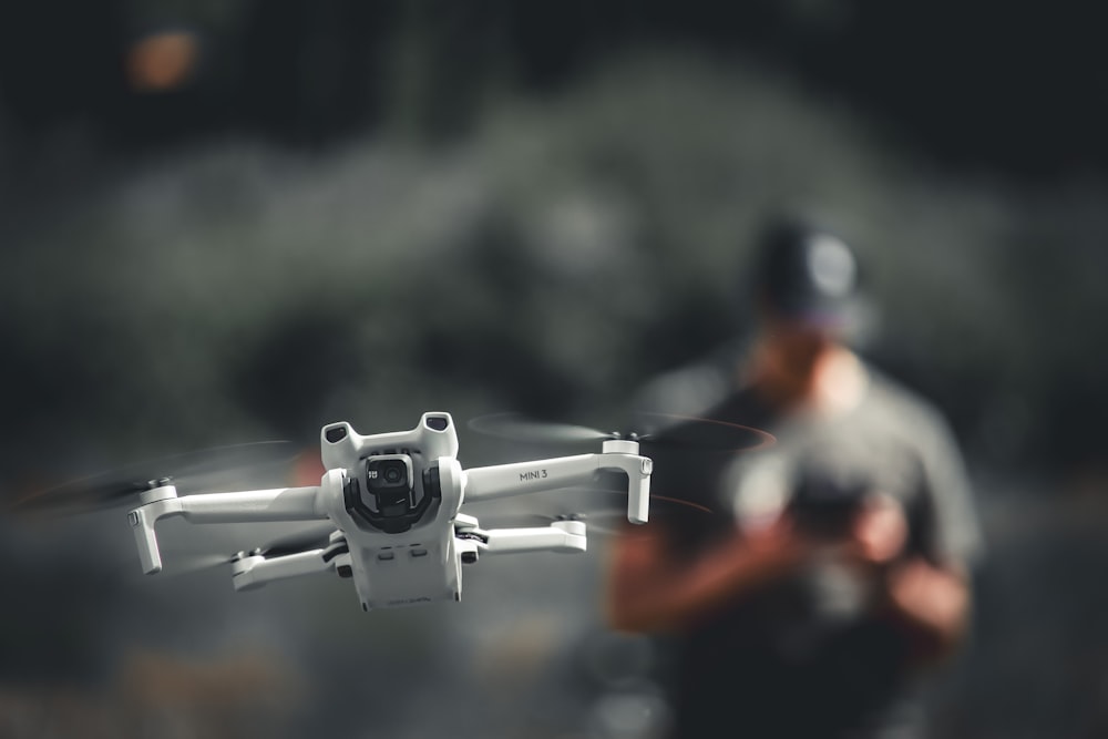 a man holding a white and black remote control flying a white and black remote control