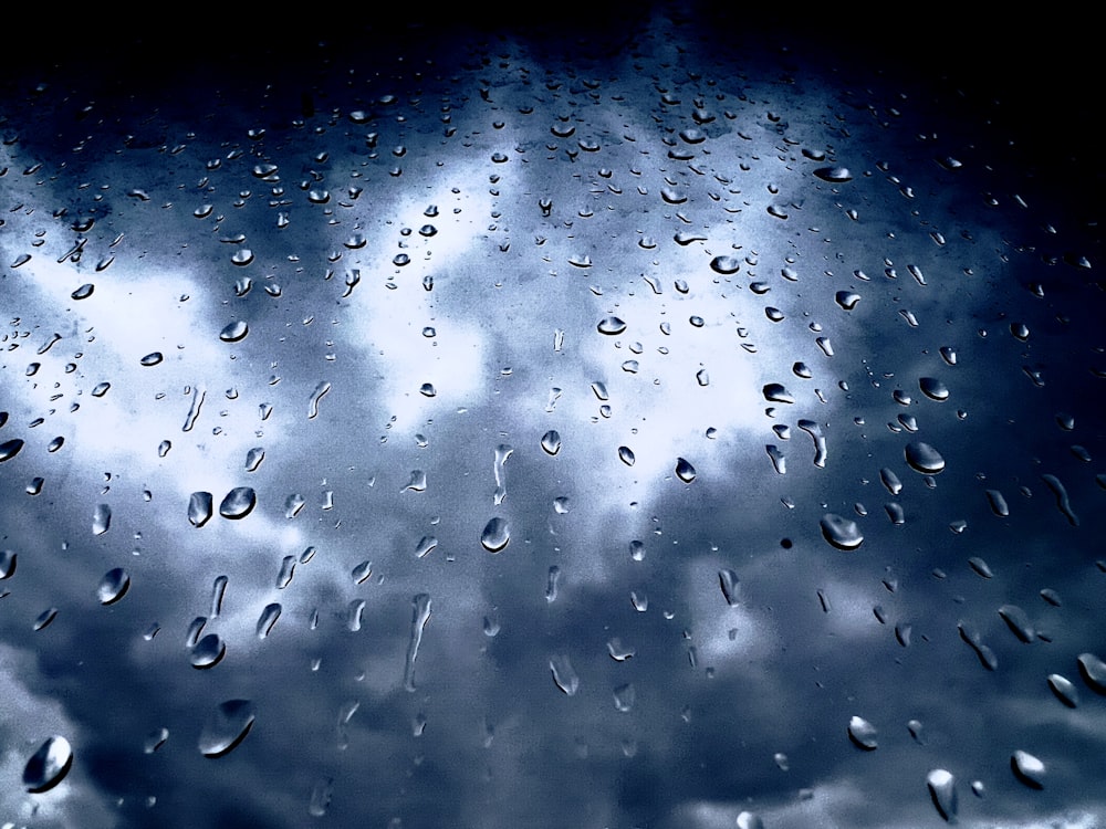 La pioggia cade su una finestra con un cielo nuvoloso sullo sfondo