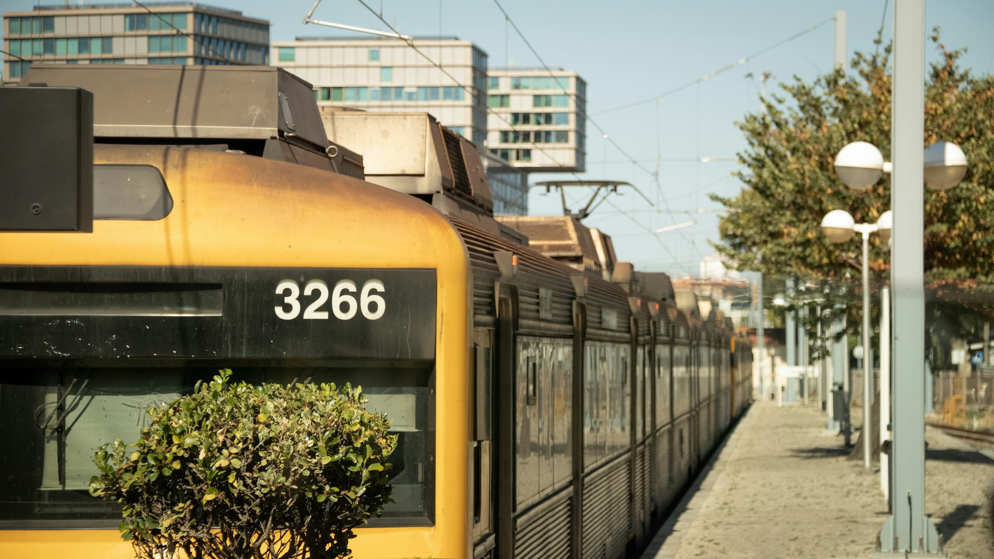 a yellow train traveling down train tracks next to tall buildings