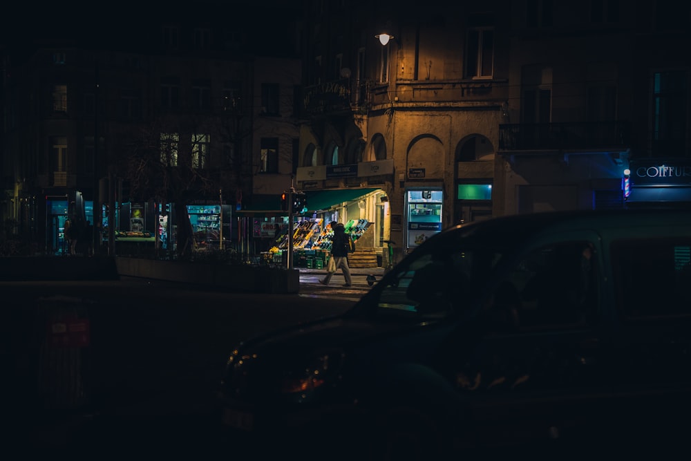 a dark city street at night with cars parked on the side of the street