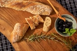 A rustic wooden board displaying assorted artisan breads and dipping oils.