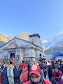 Pilgrims gathered at the ancient Kedarnath temple, wrapped in saffron shawls under a clear blue sky.