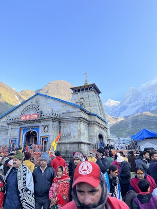 Pilgrims gathered at the ancient Kedarnath temple, wrapped in saffron shawls under a clear blue sky.