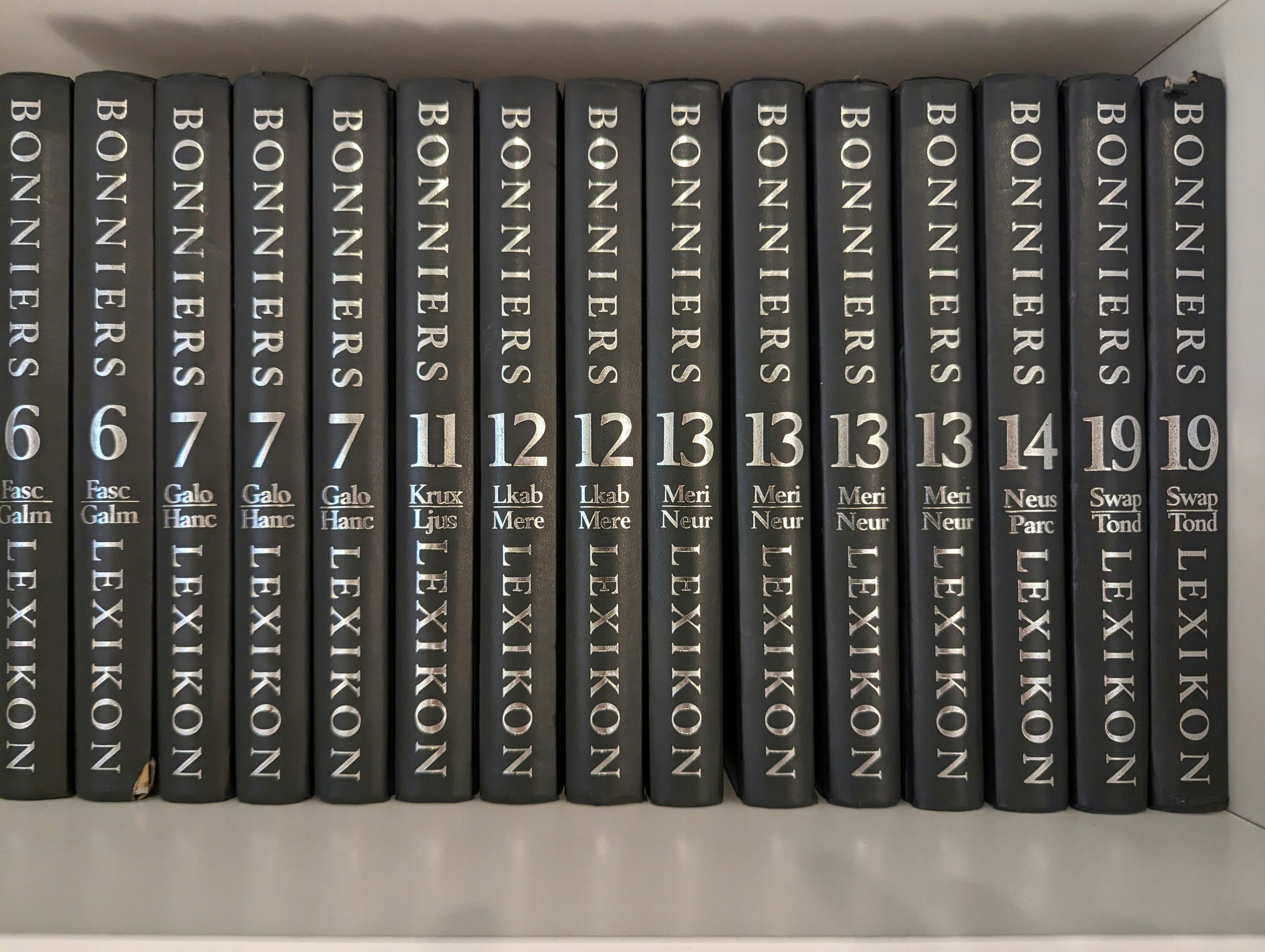 a row of black books sitting on top of a shelf