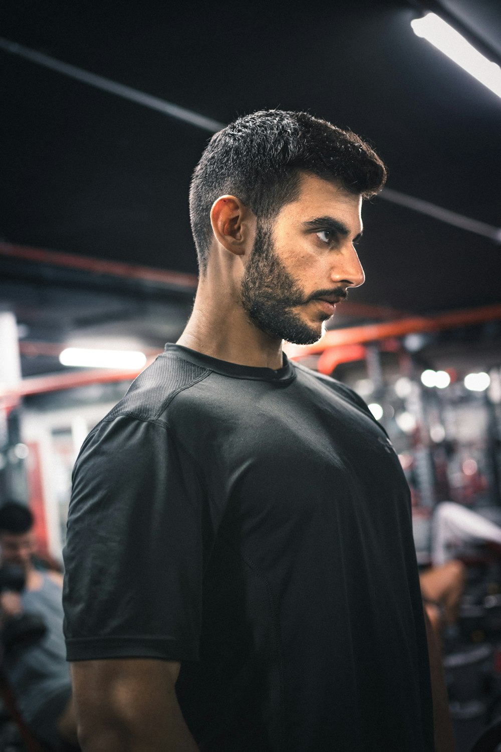 a man standing in a gym with a beard