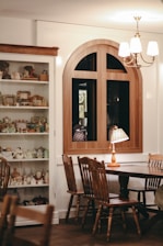 A cozy living room featuring a royal wooden table and antique-inspired chairs bathed in warm light.