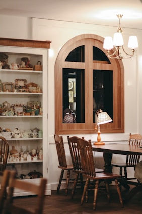 A cozy dining room featuring a wooden extendable table surrounded by matching chairs and a sideboard buffet against a softly lit wall.