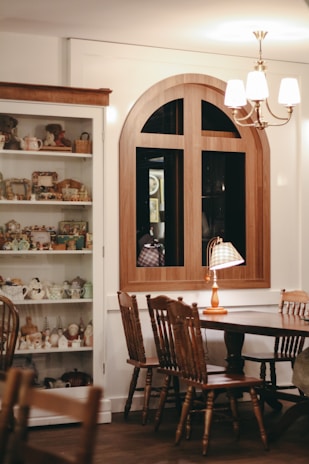 A cozy living room featuring a royal wooden table and antique-inspired chairs bathed in warm light.