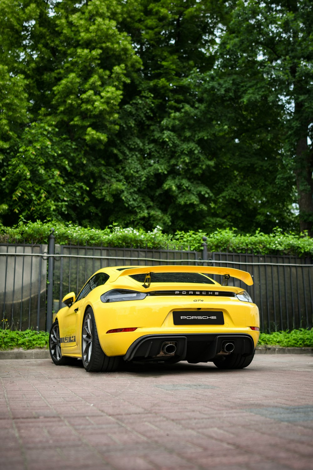 a yellow sports car parked in front of a fence
