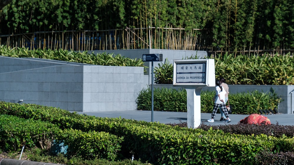 a woman walking down a sidewalk next to a sign