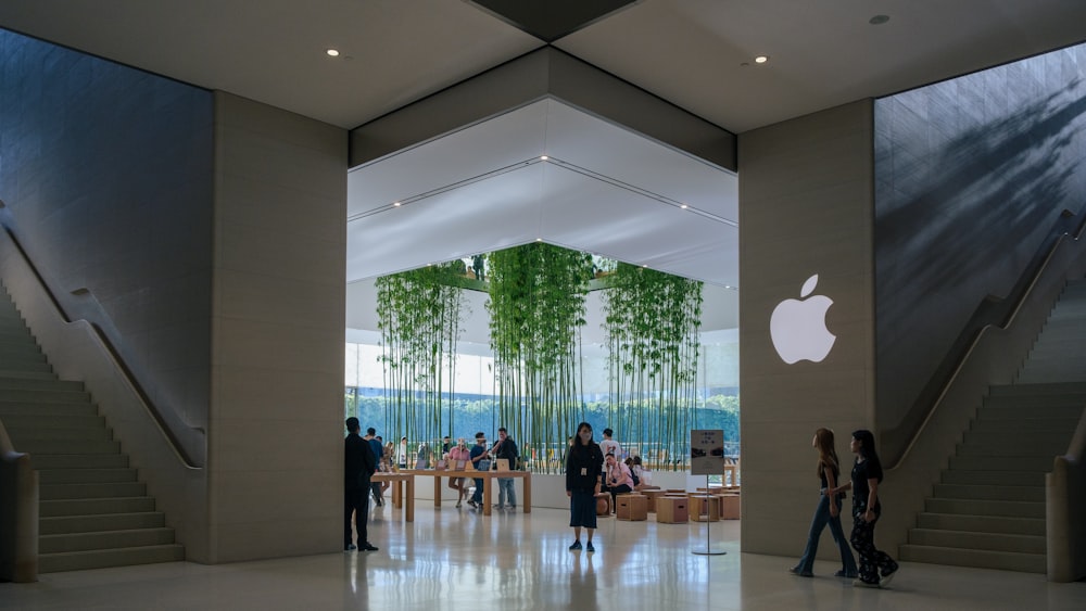 a group of people walking through an apple store