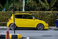 A vibrant yellow hatchback gleaming in natural daylight on a city street.