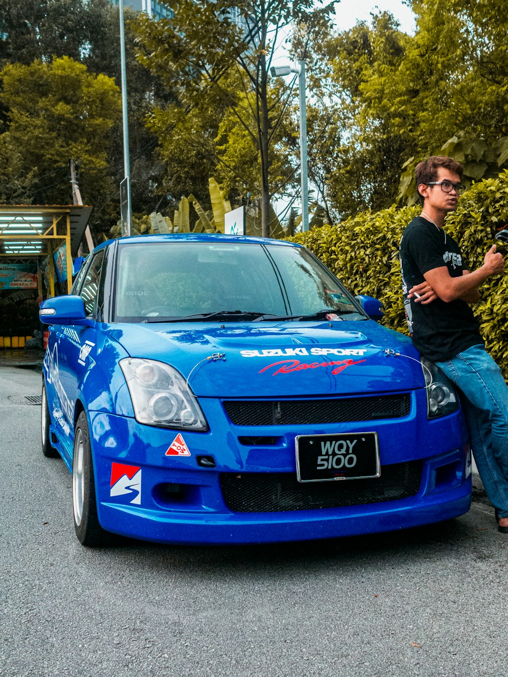 a man sitting on the hood of a blue car