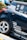 A close-up view of the rear section of a sporty car adorned with multiple brand decals including Apex, Recaro, and Power Filter. The car is navy blue with a silver stripe and features custom wheels.