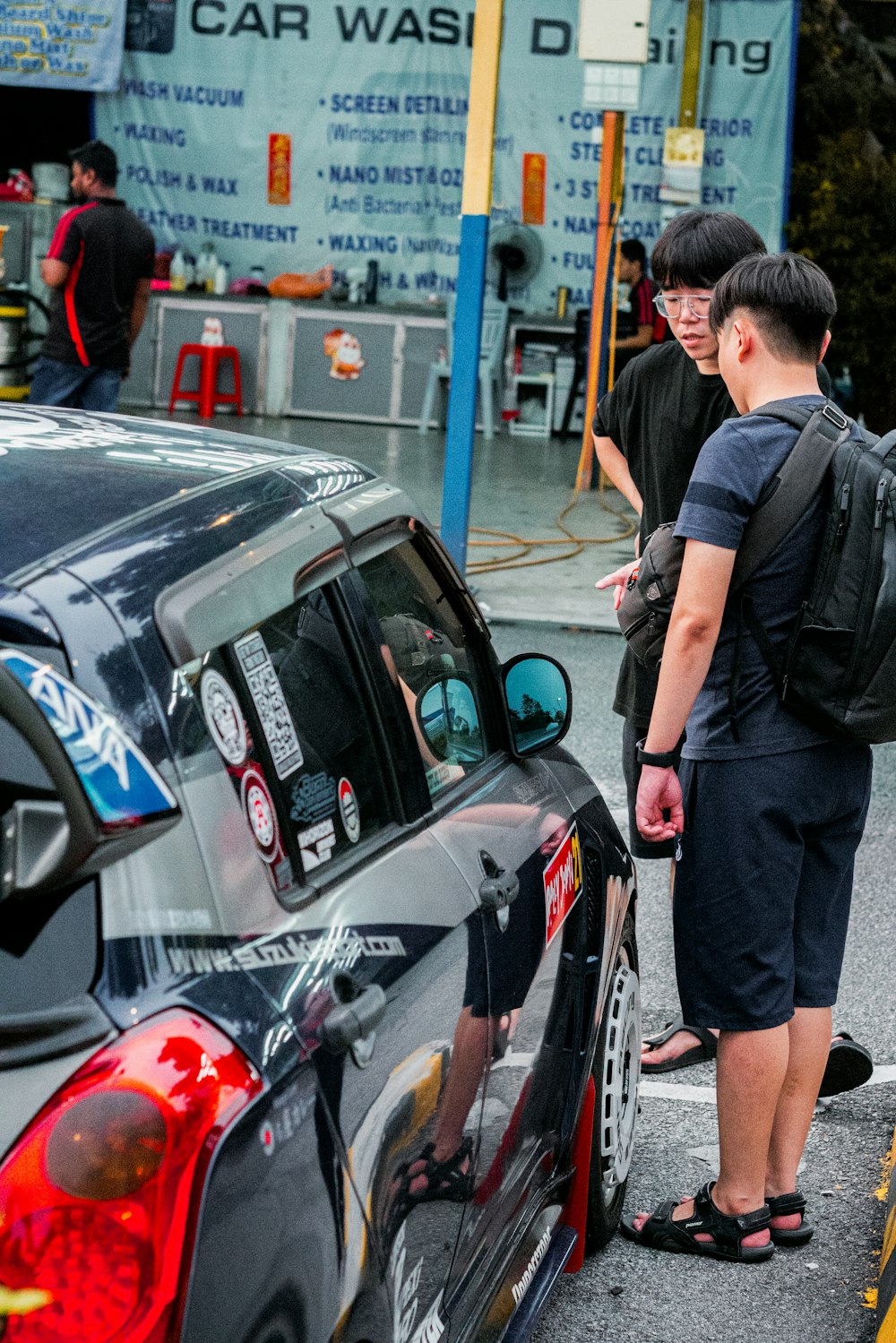 a couple of men standing next to a parked car